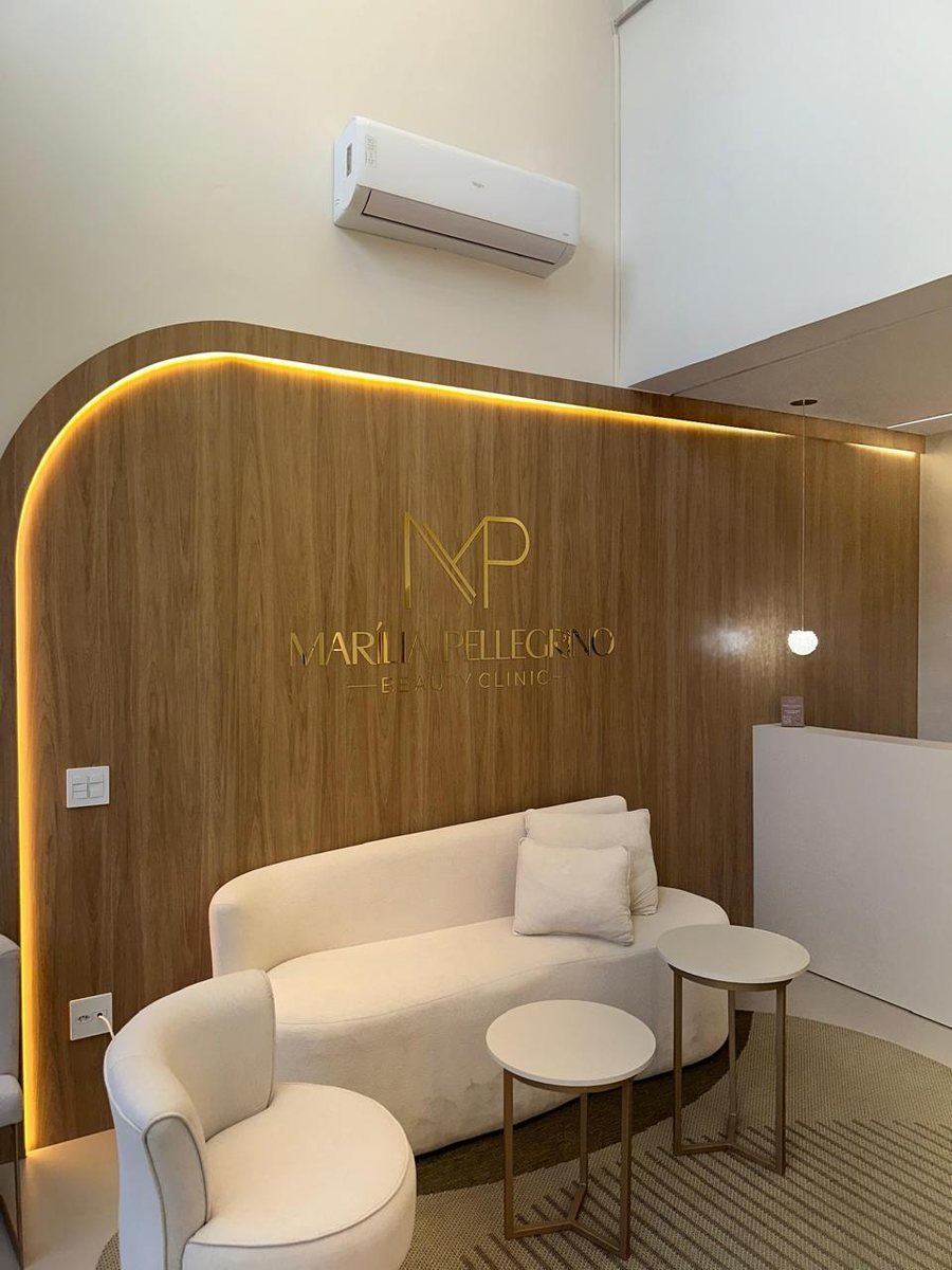 Recepção da clínica com parede em madeira e logotipo iluminado